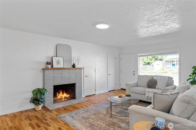659 NW New York Ave, Chehalis, WA 98532 - living area featuring a textured ceiling, a brick fireplace, and wood finished floors