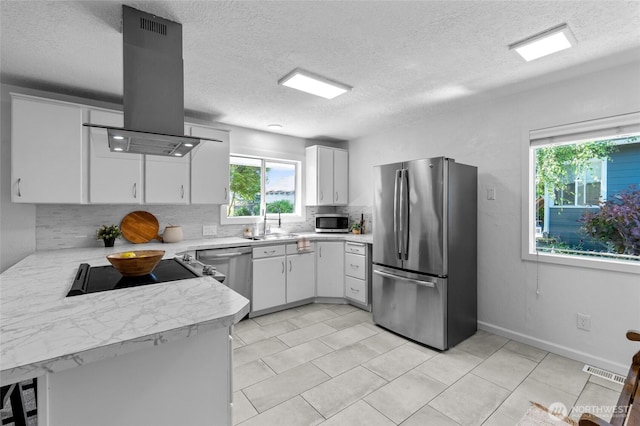659 NW New York Ave, Chehalis, WA 98532 - kitchen with appliances with stainless steel finishes, island exhaust hood, light countertops, tasteful backsplash, and a textured ceiling
