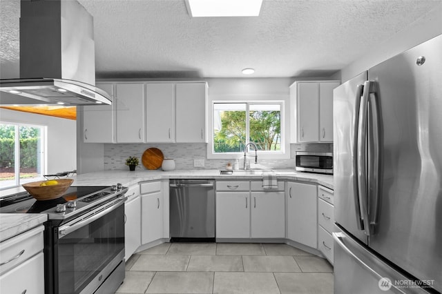659 NW New York Ave, Chehalis, WA 98532 - kitchen featuring stainless steel appliances, island exhaust hood, a sink, healthy amount of natural light, and a textured ceiling