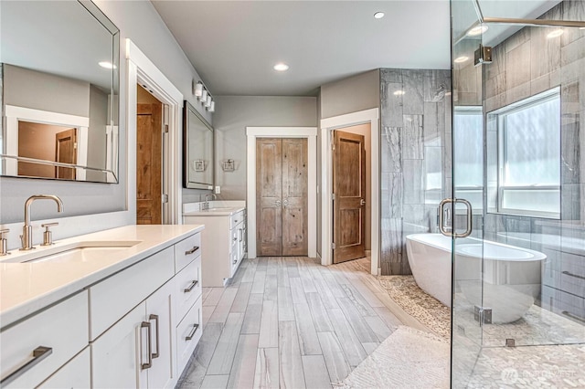 4942 Hurst Landing Rd, Rock Island, WA 98850 - bathroom with two vanities, a freestanding tub, a shower stall, wood finish floors, and recessed lighting