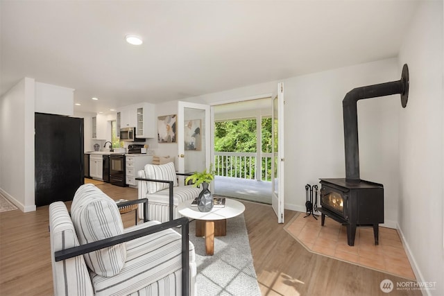 8021 NE Sandpiper Ln, Bainbridge Island, WA 98110 - living room with baseboards, a wood stove, light wood-type flooring, and recessed lighting