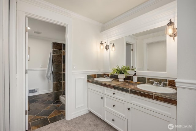 8021 NE Sandpiper Ln, Bainbridge Island, WA 98110 - full bathroom with double vanity, tiled shower, wainscoting, ornamental molding, and stone finish floors