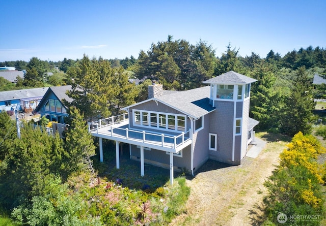 530 Sand Dune Ave SW, Ocean Shores, WA 98569 - rear view of house featuring a chimney, roof with shingles, a wooden deck, and driveway