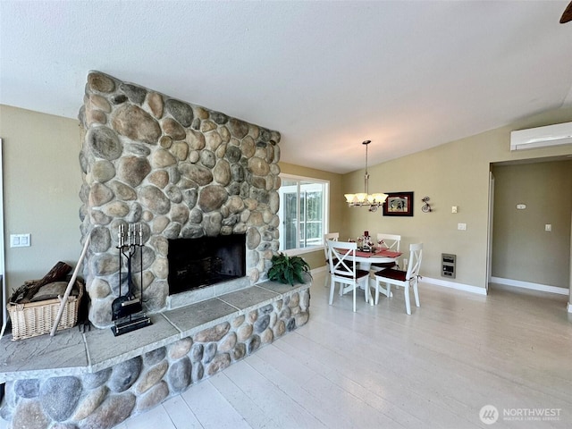 530 Sand Dune Ave SW, Ocean Shores, WA 98569 - living area with a stone fireplace, wood finished floors, an AC wall unit, a chandelier, and lofted ceiling