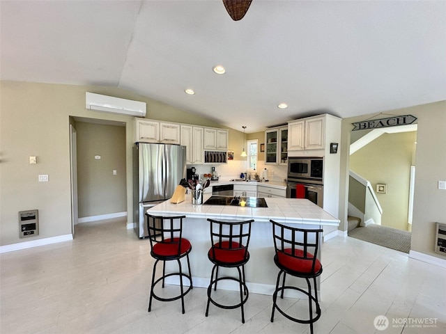 530 Sand Dune Ave SW, Ocean Shores, WA 98569 - kitchen with stainless steel appliances, a wall unit AC, a kitchen bar, vaulted ceiling, and a center island
