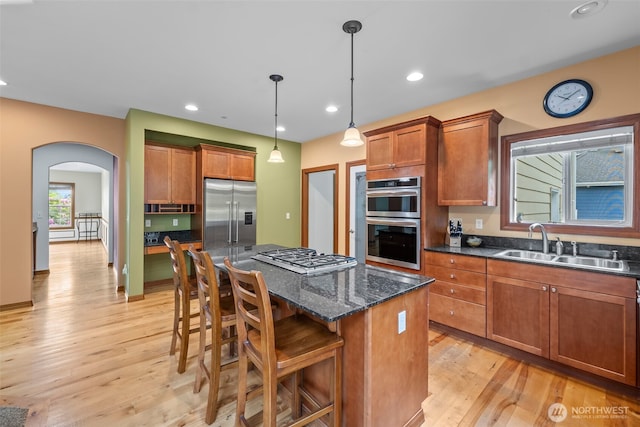2616 171st Ave E, Lake Tapps, WA 98391 - kitchen with appliances with stainless steel finishes, a sink, arched walkways, light wood-style floors, and brown cabinets