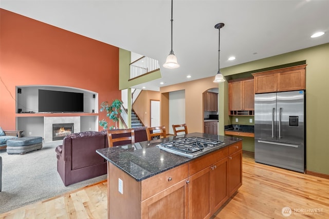 2616 171st Ave E, Lake Tapps, WA 98391 - kitchen with stainless steel appliances, light wood-style floors, arched walkways, dark stone counters, and a kitchen island