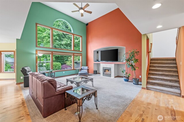 2616 171st Ave E, Lake Tapps, WA 98391 - living area with a ceiling fan, a towering ceiling, stairs, a tiled fireplace, and baseboards