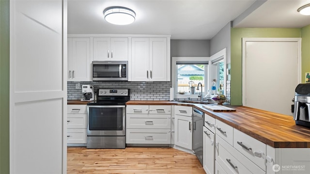 1109 University St, Walla Walla, WA 99362 - kitchen with butcher block countertops, stainless steel appliances, a sink, white cabinetry, and light wood-style floors