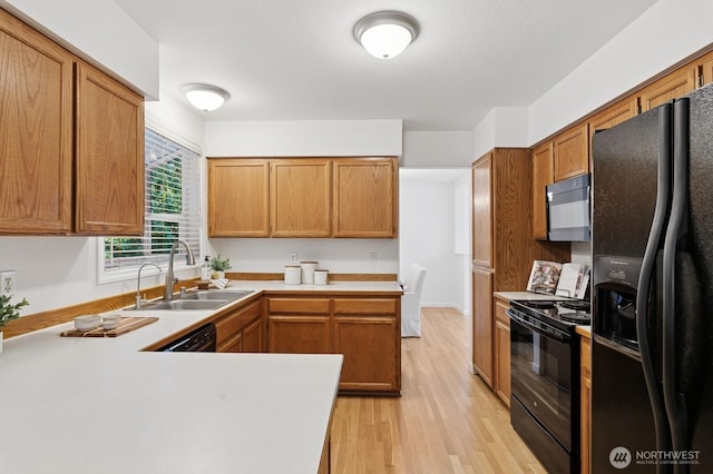 1826 168th Pl SE, Mill Creek, WA 98012 - kitchen featuring black appliances, light wood-style floors, a sink, light countertops, and brown cabinets