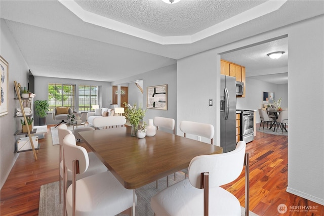 18802 10th Avenue Ct E, Tacoma, WA 98387 - dining space with wood finished floors, a textured ceiling, a tray ceiling, and baseboards