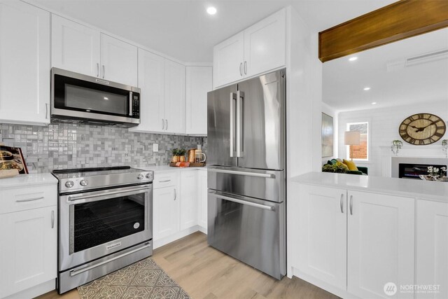 8042 19th Ave NW, Seattle, WA 98117 - kitchen featuring appliances with stainless steel finishes, light countertops, tasteful backsplash, white cabinets, and recessed lighting