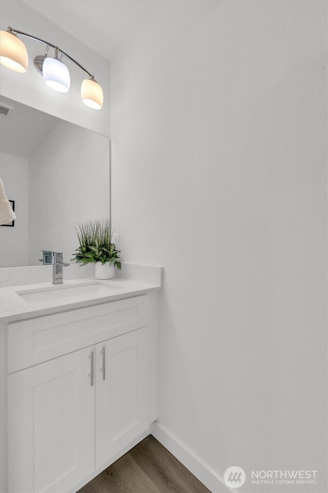 8042 19th Ave NW, Seattle, WA 98117 - bathroom featuring wood finished floors, vanity, and baseboards