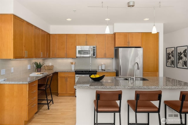 145 Ferncliff Ave NE Unit D338, Bainbridge Island, WA 98110 - kitchen with stainless steel appliances, a sink, light wood finished floors, a kitchen bar, and light stone counters