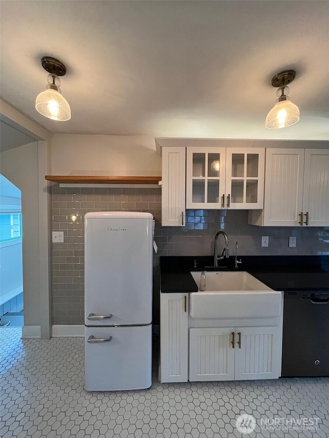 908 Washington Ave N, Long Beach, WA 98631 - kitchen featuring black dishwasher, freestanding refrigerator, dark countertops, glass insert cabinets, and white cabinets