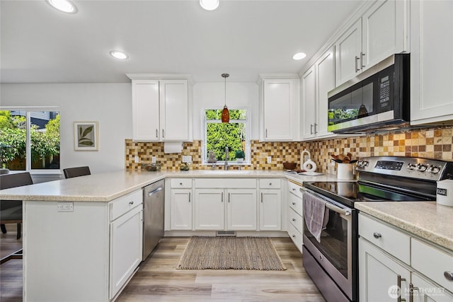 3534 SW Monroe St, Seattle, WA 98126 - kitchen featuring stainless steel appliances, a peninsula, healthy amount of natural light, white cabinetry, and recessed lighting