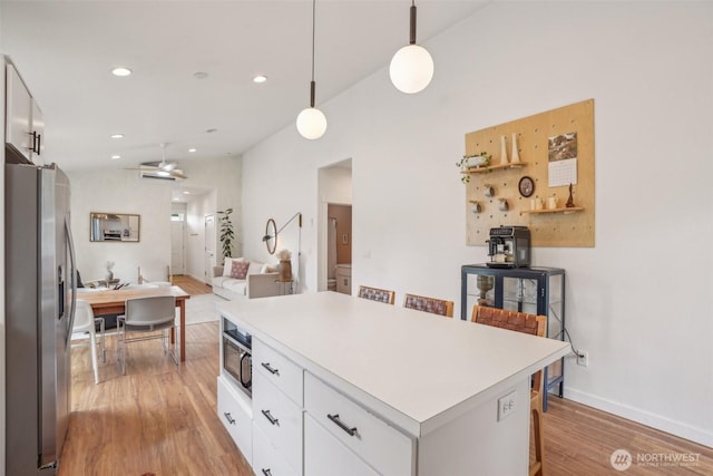 201 SE Alder St, Winlock, WA 98596 - kitchen featuring stainless steel refrigerator with ice dispenser, light wood-style floors, a kitchen island, white cabinets, and light countertops
