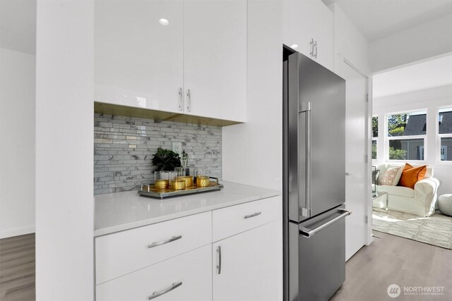 8040 19th Ave NW, Seattle, WA 98117 - kitchen with high quality fridge, light wood-type flooring, light countertops, tasteful backsplash, and white cabinets