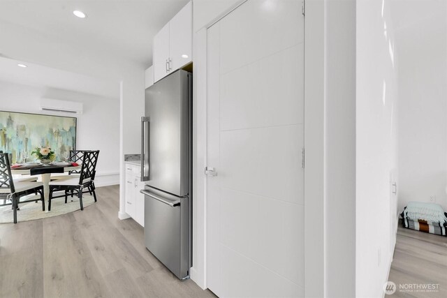 8040 19th Ave NW, Seattle, WA 98117 - kitchen with freestanding refrigerator, a wall mounted AC, white cabinetry, light wood-type flooring, and modern cabinets