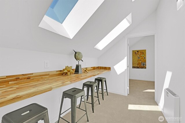 8040 19th Ave NW, Seattle, WA 98117 - kitchen featuring a skylight, vaulted ceiling, carpet, a kitchen bar, and baseboards
