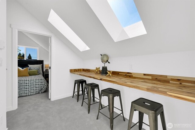 8040 19th Ave NW, Seattle, WA 98117 - kitchen featuring a skylight, lofted ceiling, carpet flooring, a breakfast bar area, and wood counters