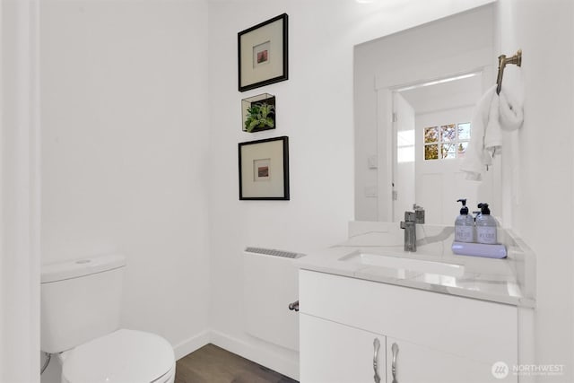 8040 19th Ave NW, Seattle, WA 98117 - bathroom featuring toilet, vanity, baseboards, and wood finished floors