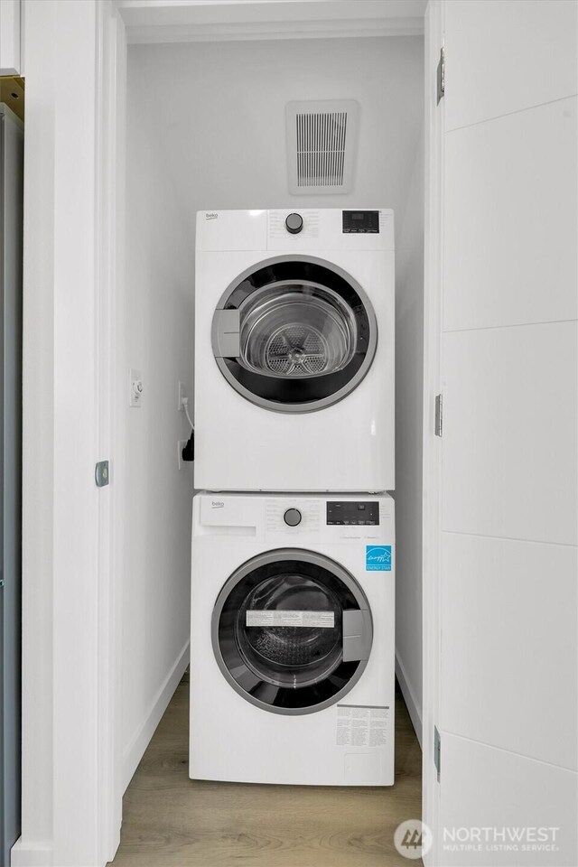 8040 19th Ave NW, Seattle, WA 98117 - laundry room featuring stacked washer and clothes dryer, wood finished floors, and baseboards