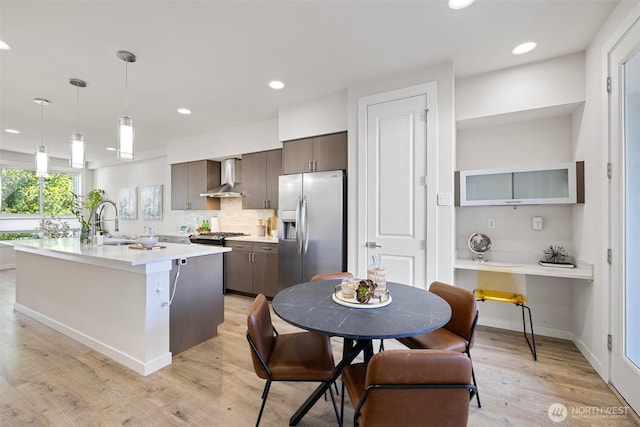 684 SW 100th St, Seattle, WA 98106 - kitchen featuring stainless steel fridge, wall chimney exhaust hood, a sink, light countertops, and dark brown cabinetry