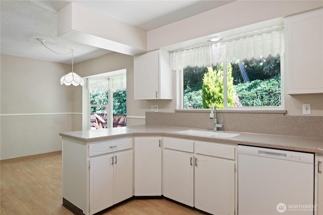2207 Burcham St, Kelso, WA 98626 - kitchen with white dishwasher, a sink, a peninsula, light countertops, and white cabinets