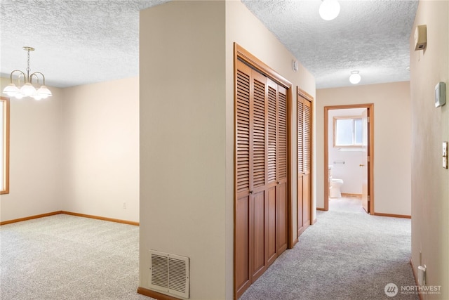 2207 Burcham St, Kelso, WA 98626 - hallway featuring a textured ceiling, carpet floors, baseboards, and a chandelier