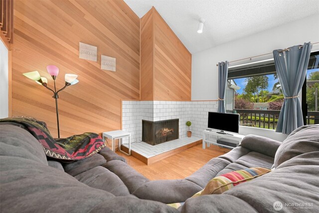 7530 Birch Bay Dr Unit 210, Blaine, WA 98230 - living area with wood walls, a brick fireplace, wood finished floors, lofted ceiling, and a textured ceiling