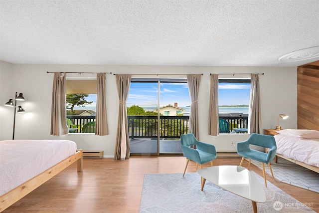 7530 Birch Bay Dr Unit 210, Blaine, WA 98230 - bedroom featuring a textured ceiling, access to outside, multiple windows, wood finished floors, and baseboard heating