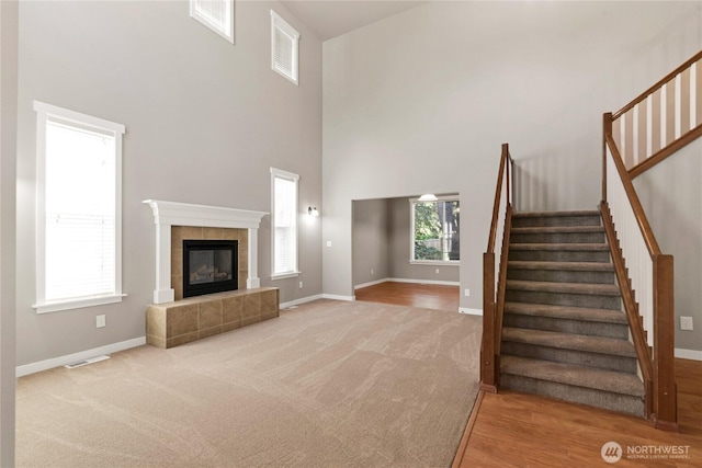 4507 Trenton Loop SE, Olympia, WA 98501 - unfurnished living room with stairway, baseboards, a high ceiling, carpet flooring, and a tiled fireplace