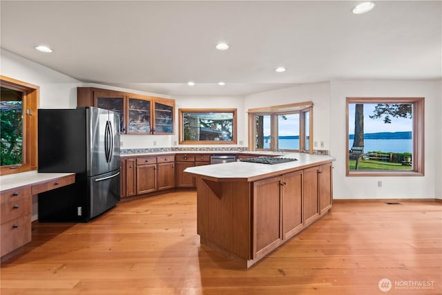 2548 S Camano Dr, Camano Island, WA 98282 - kitchen with stainless steel appliances, a peninsula, brown cabinetry, light countertops, and glass insert cabinets