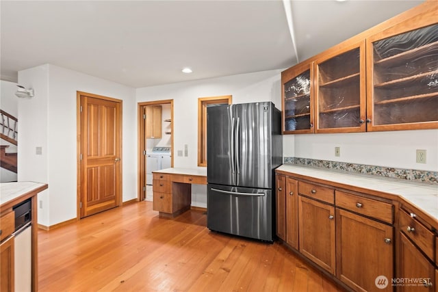 2548 S Camano Dr, Camano Island, WA 98282 - kitchen featuring freestanding refrigerator, independent washer and dryer, light wood-style flooring, tile countertops, and glass insert cabinets