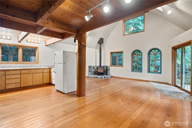 2548 S Camano Dr, Camano Island, WA 98282 - kitchen with freestanding refrigerator, rail lighting, a wood stove, light countertops, and a towering ceiling