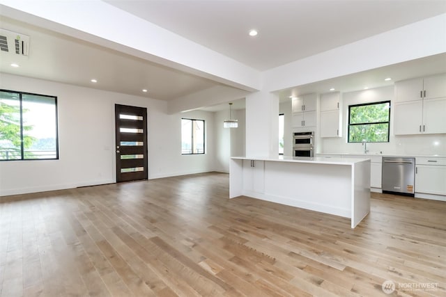7253 S Taft St, Seattle, WA 98178 - kitchen featuring stainless steel appliances, open floor plan, light countertops, light wood-style floors, and white cabinets