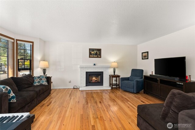 4404 29th Ave SE, Lacey, WA 98503 - living area featuring light wood-style flooring, a textured ceiling, and a brick fireplace