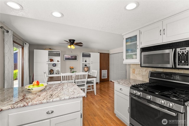 4404 29th Ave SE, Lacey, WA 98503 - kitchen featuring appliances with stainless steel finishes, ceiling fan, white cabinetry, backsplash, and light wood-type flooring