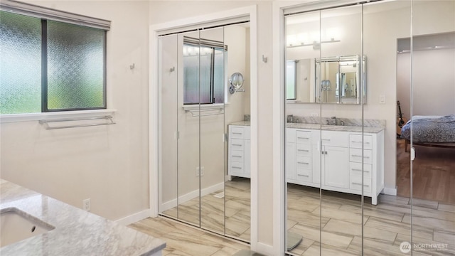 1525 E Catalpa St, Othello, WA 99344 - ensuite bathroom featuring vanity, marble look tiles, and baseboards