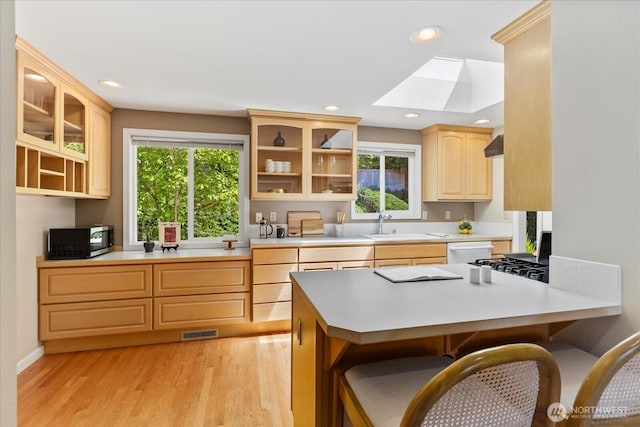 22035 99th Pl W, Edmonds, WA 98020 - kitchen featuring a skylight, light brown cabinets, a breakfast bar, a peninsula, and recessed lighting
