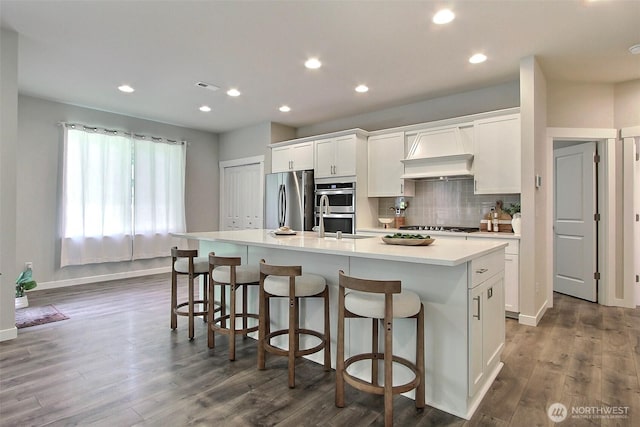 3007 Fiddleback St NE, Lacey, WA 98516 - kitchen with appliances with stainless steel finishes, a center island with sink, white cabinets, a breakfast bar, and decorative backsplash