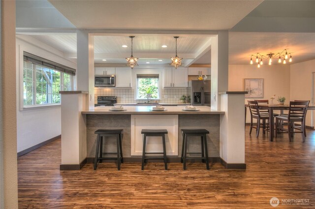 872 Albion Ave SE, Ocean Shores, WA 98569 - kitchen with appliances with stainless steel finishes, dark wood-style flooring, a breakfast bar area, backsplash, and recessed lighting
