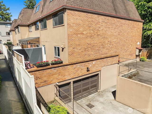 379 100th Ave NE Unit A, Bellevue, WA 98004 - view of side of home featuring mansard roof, brick siding, a shingled roof, and an attached garage