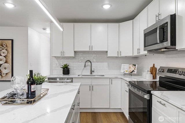 4126 19th Ave SW, Seattle, WA 98106 - kitchen with appliances with stainless steel finishes, a sink, white cabinetry, and light wood-type flooring
