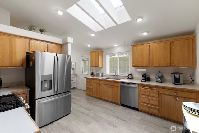 6124 91st St E, Puyallup, WA 98371 - kitchen featuring appliances with stainless steel finishes, a sink, a skylight, light countertops, and light wood finished floors