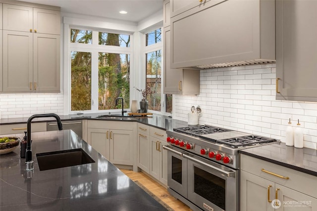21412 NE 16th St, Sammamish, WA 98074 - kitchen featuring range with two ovens, a sink, wall chimney exhaust hood, tasteful backsplash, and recessed lighting
