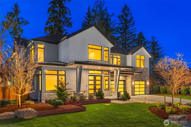 21412 NE 16th St, Sammamish, WA 98074 - back of house at twilight with stone siding, driveway, a lawn, an attached garage, and metal roof