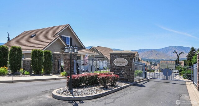 1494 Eastmont Ave Unit 58, East Wenatchee, WA 98802 - view of asphalt street with a gate, curbs, a mountain view, a gated entry, and street lights