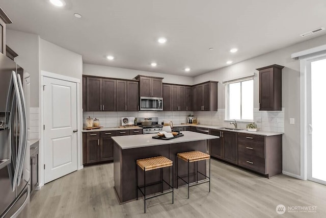 768 SE 11th Pl Lot 05, North Bend, WA 98045 - kitchen with appliances with stainless steel finishes, light wood-style flooring, a sink, a kitchen bar, and recessed lighting